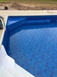 Close-up of an inground pool with a blue patterned liner and submerged entry steps